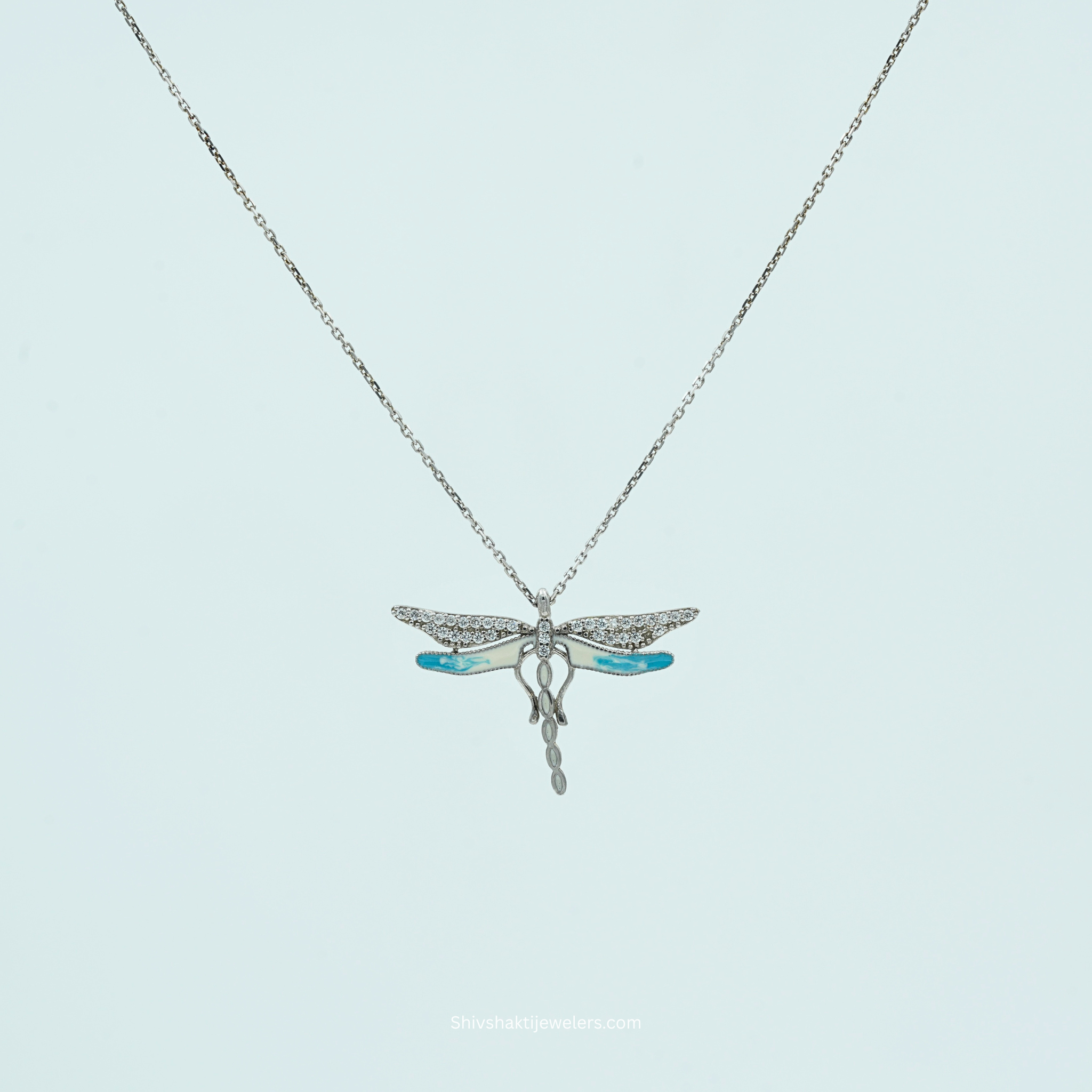 Silver necklace with a dragonfly pendant on a light blue background