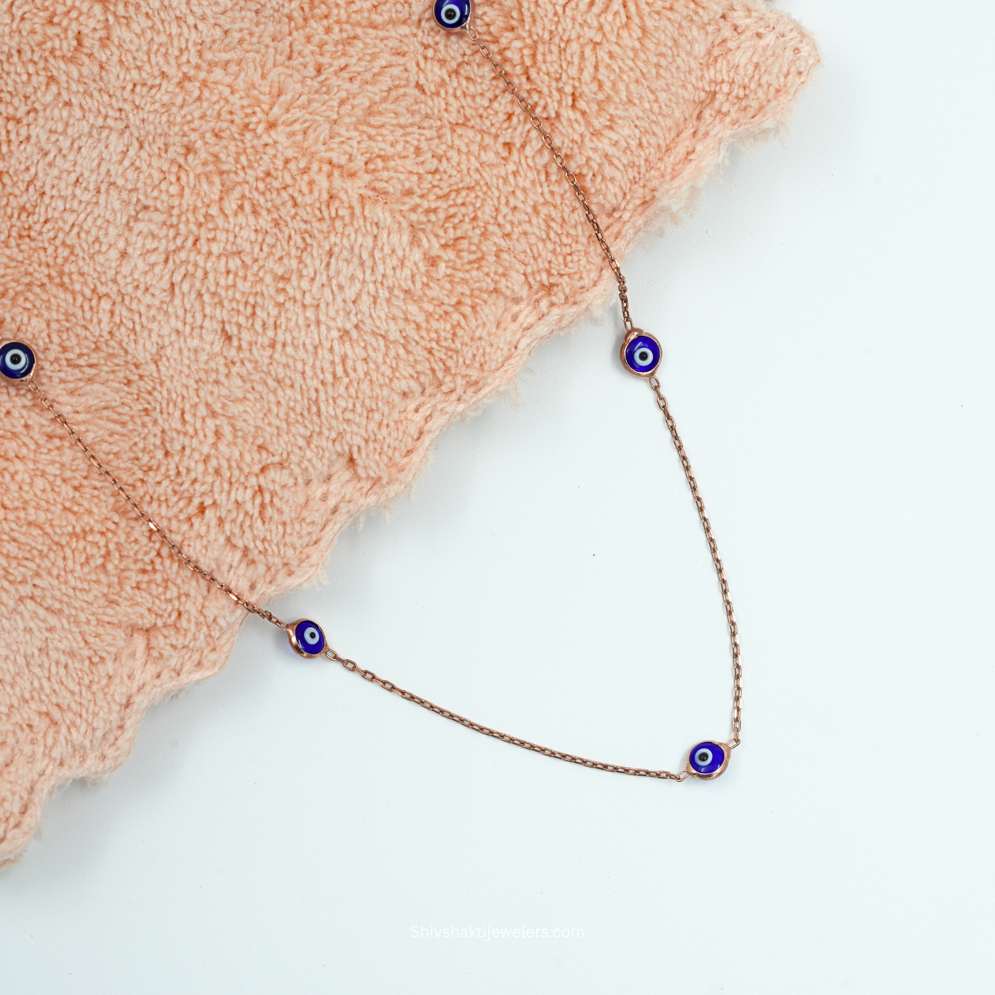 Flatlay view of 925 Sterling Silver Evil Eye Necklace with rose gold chain and blue Nazar beads