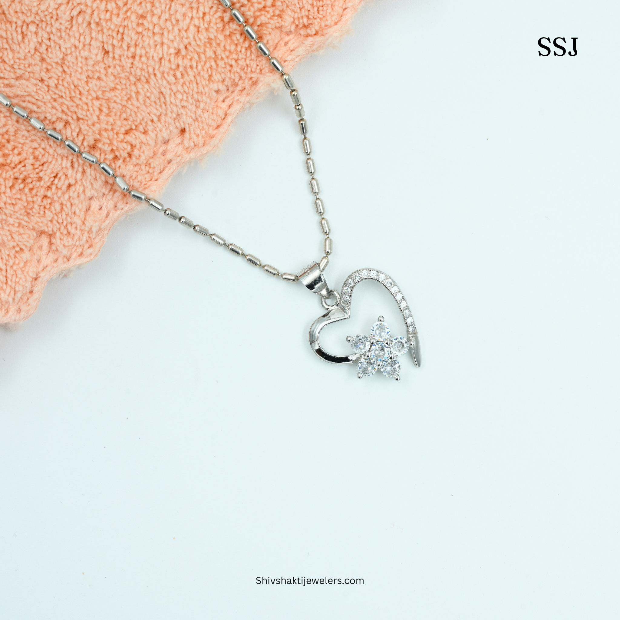 Silver heart-shaped necklace with a pendant on a white background