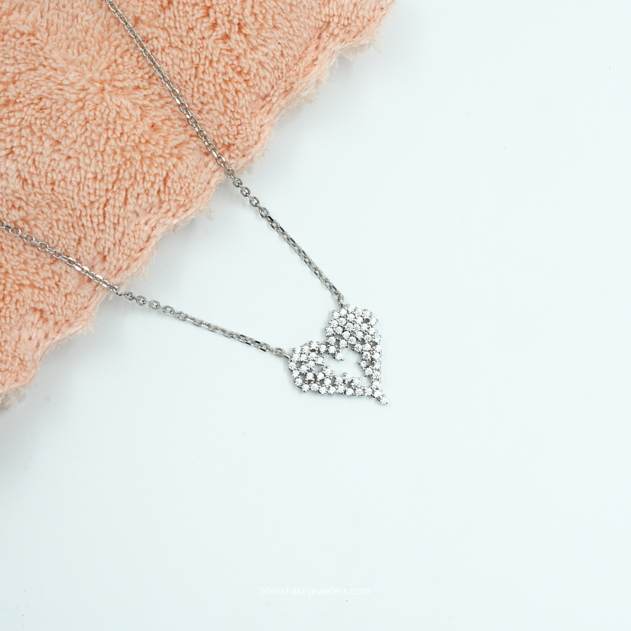 Silver necklace with a leaf-shaped pendant on a light background
