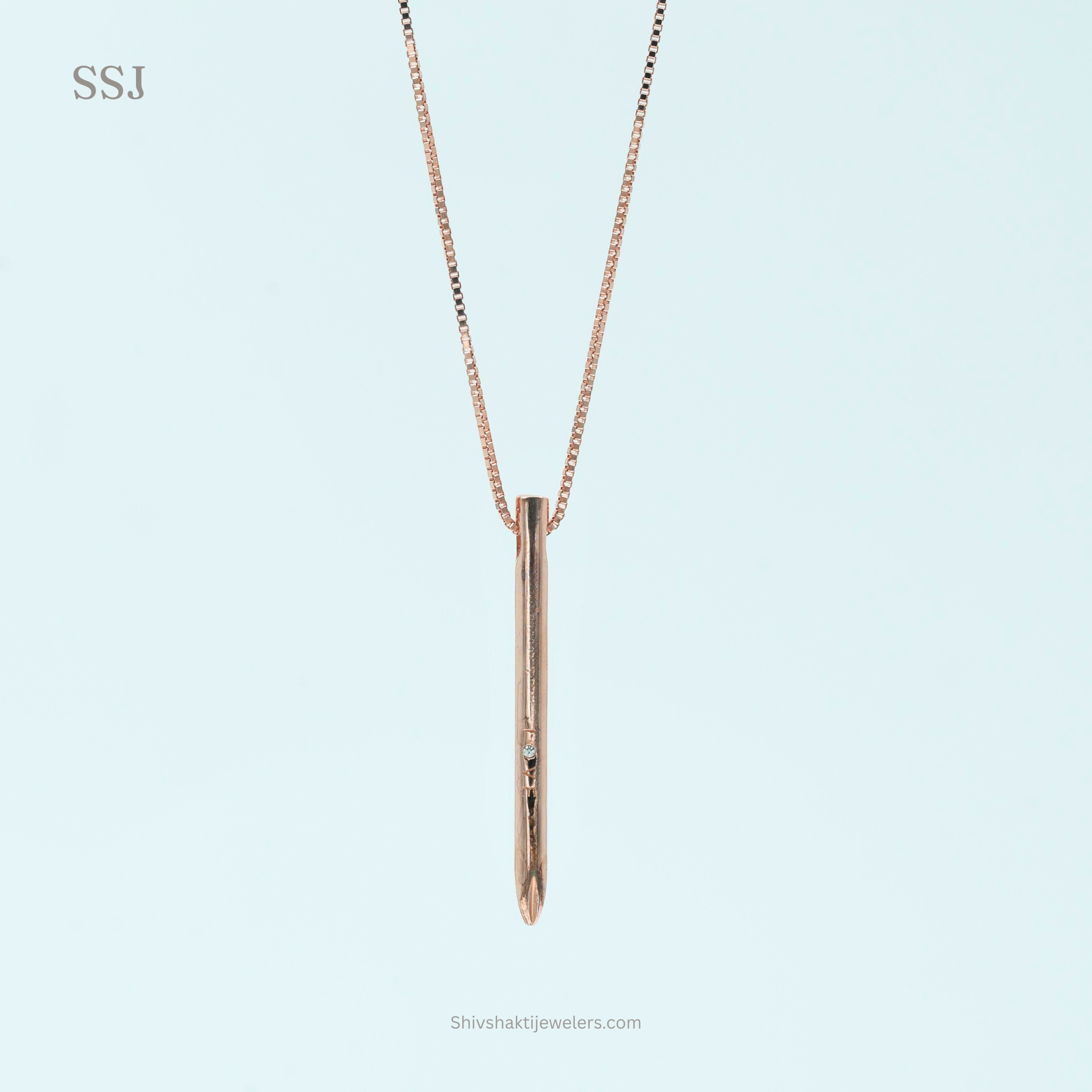 Rose gold necklace with a vertical pendant on a light blue background