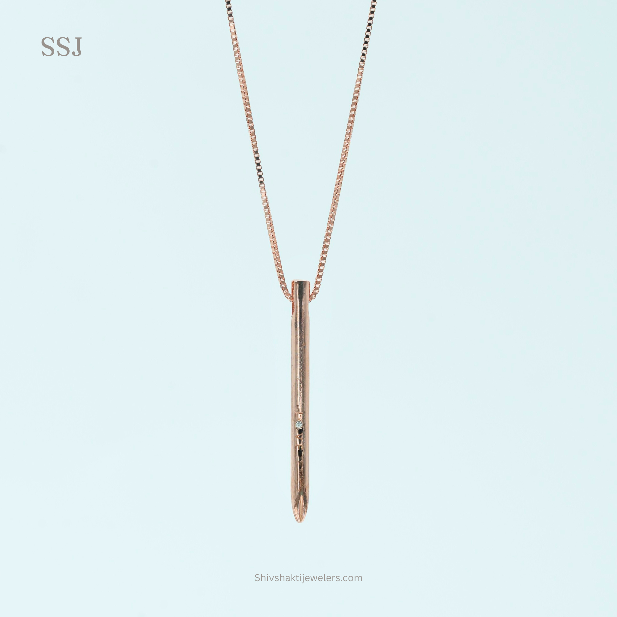 Rose gold necklace with a vertical pendant on a light blue background