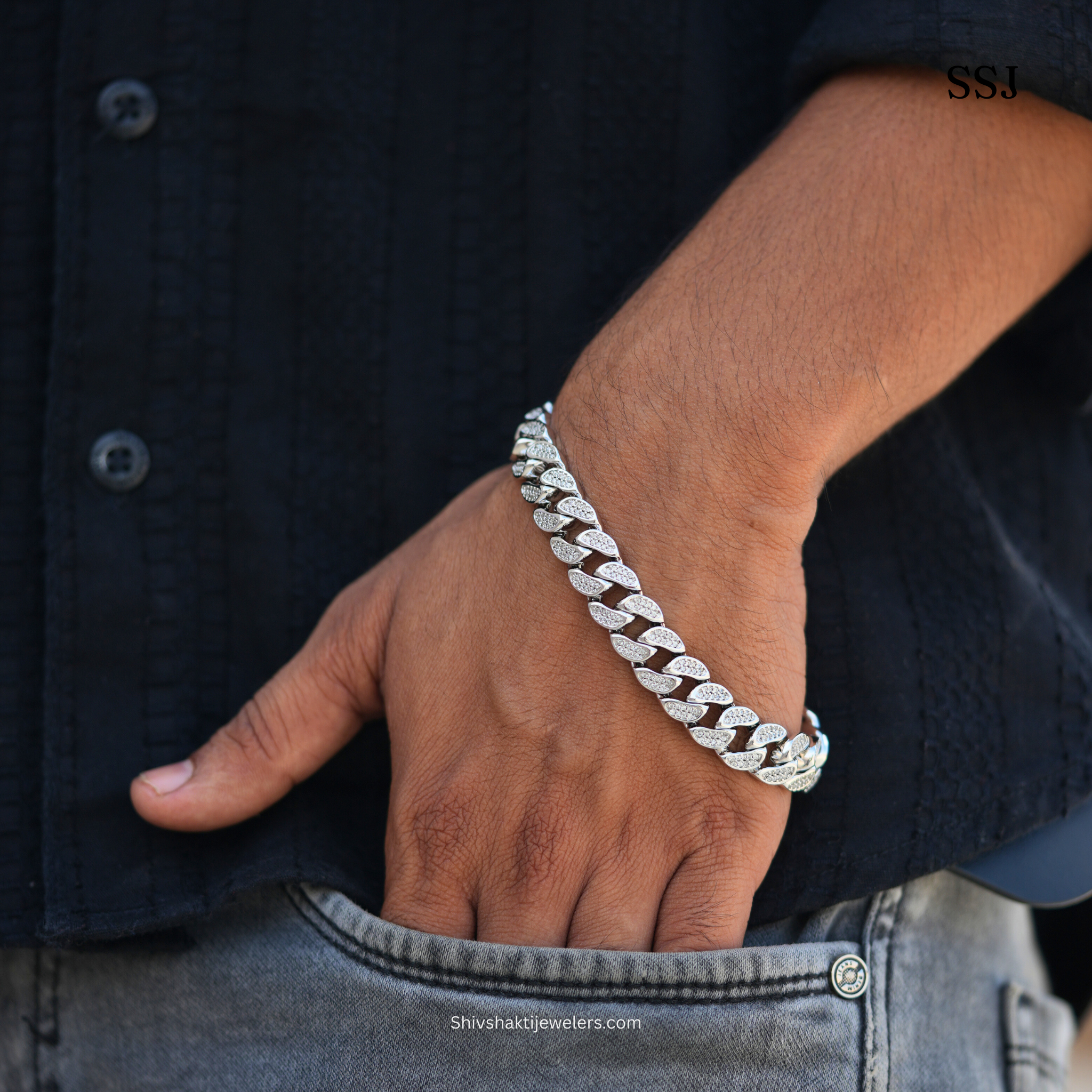 Silver bracelet on a wrist with a dark shirt and jeans background