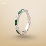 Silver ring with green gemstones on a beige background