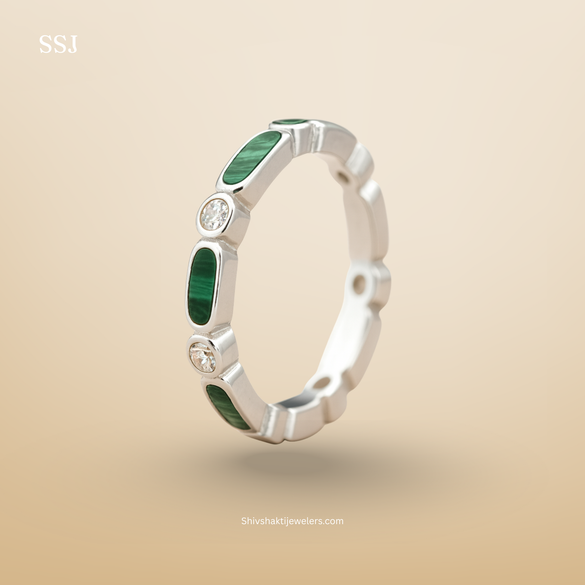 Silver ring with green gemstones on a beige background