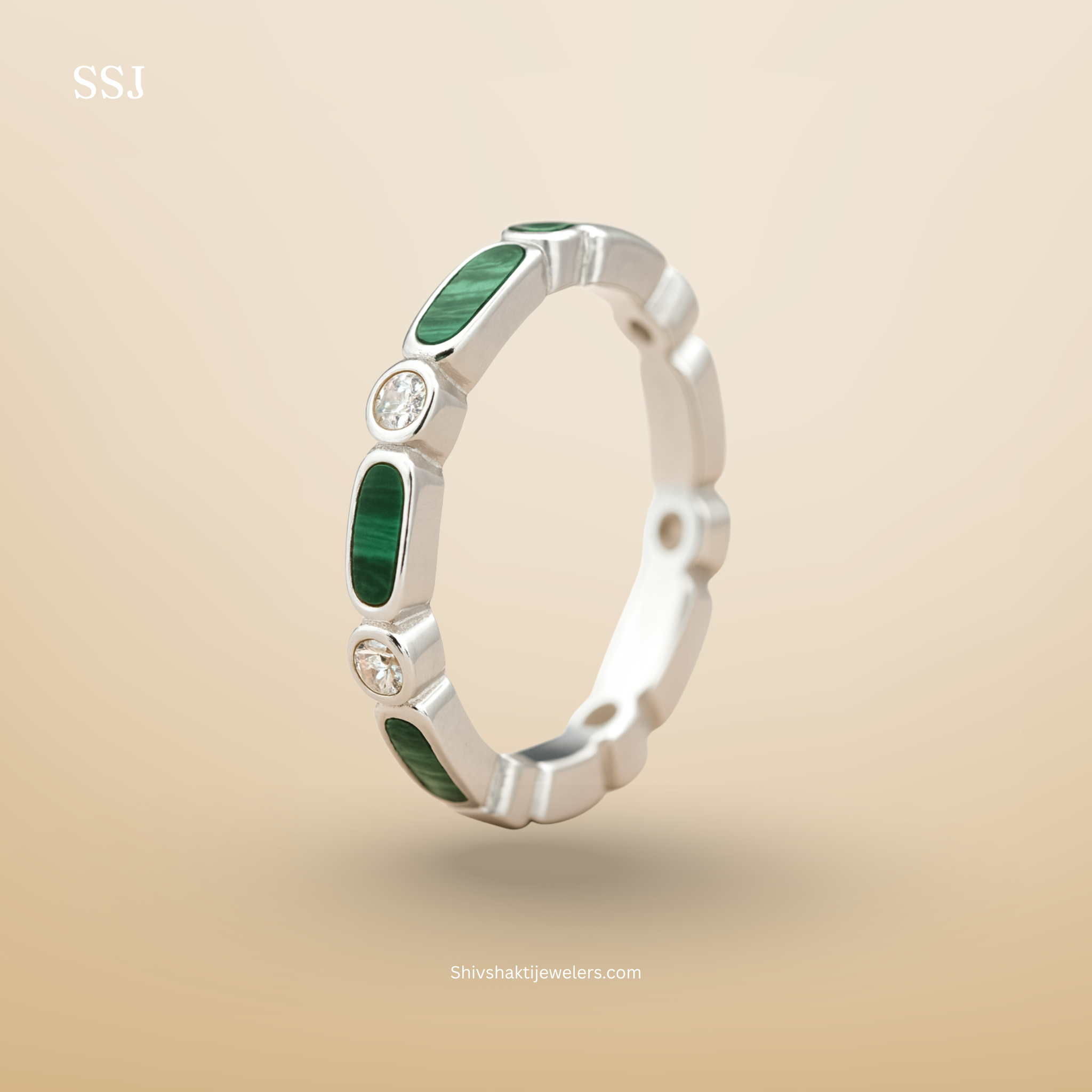 Silver ring with green gemstones on a beige background