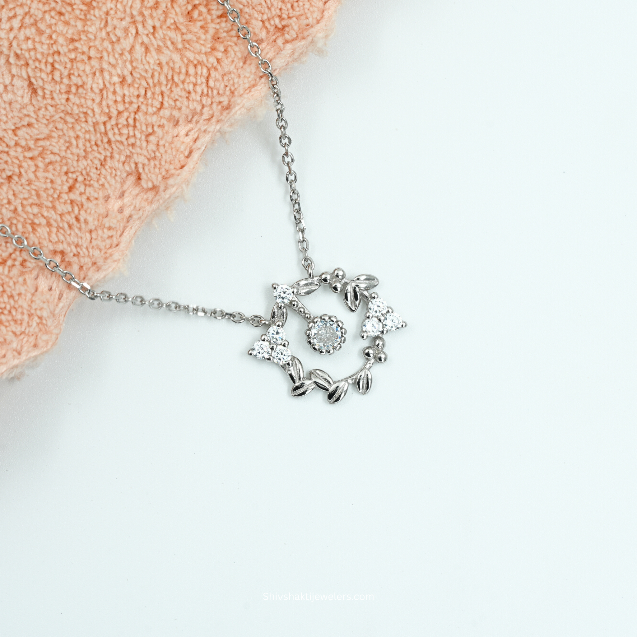 Silver necklace with a heart-shaped pendant on a white background