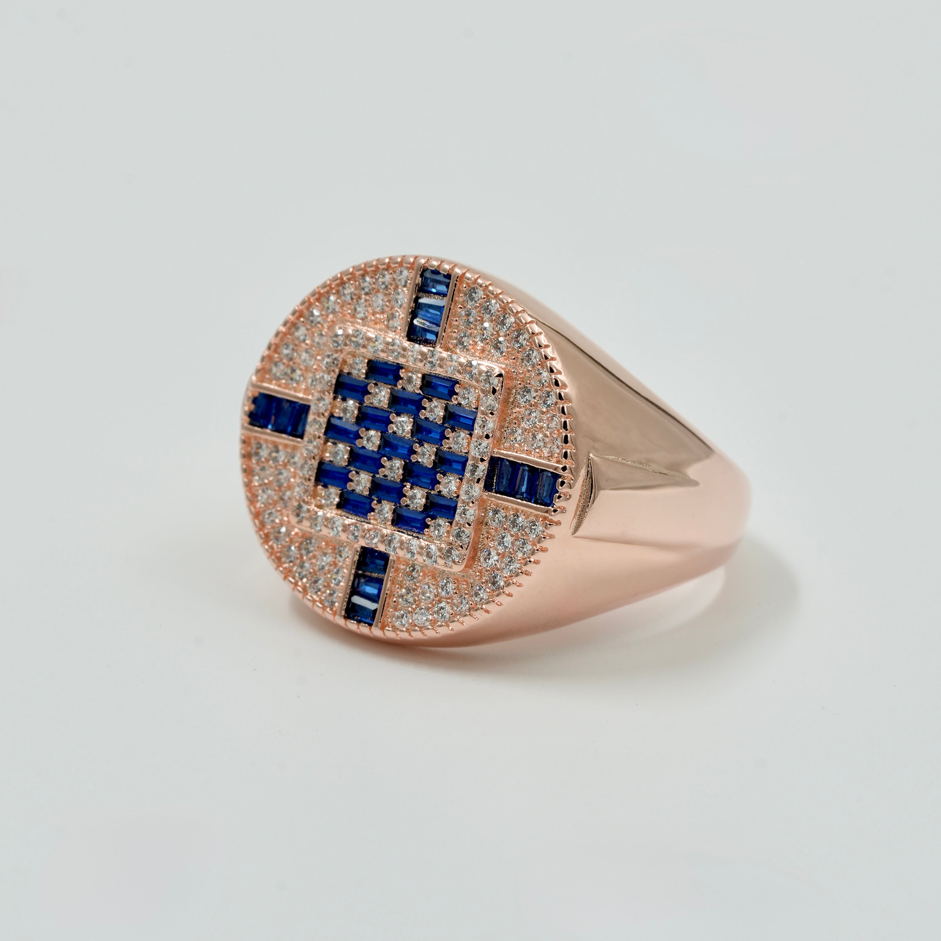 Rose gold ring with blue gemstones on a light gray background