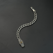 Oxidized silver lion head bracelet with emerald stone inlays on black background