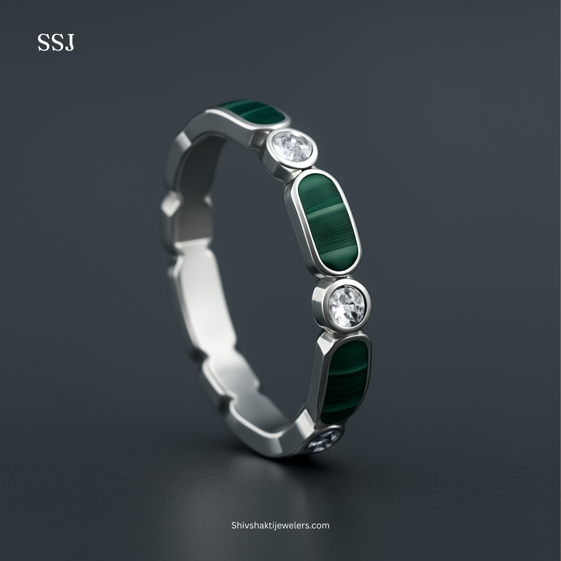 Silver ring with green gemstones and clear stones on a dark background