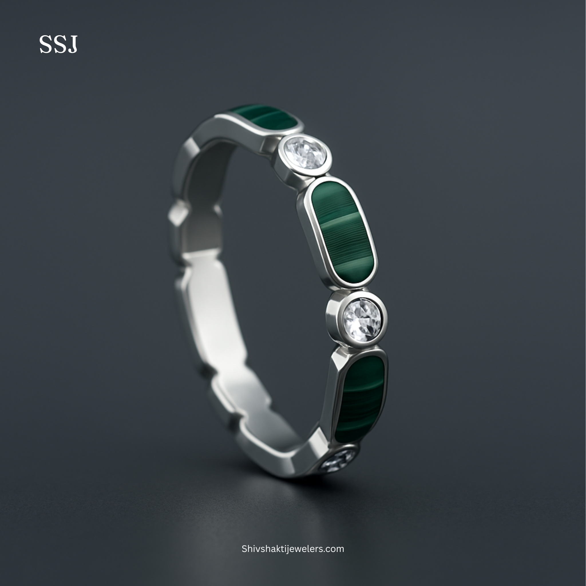 Silver ring with green gemstones and clear stones on a dark background