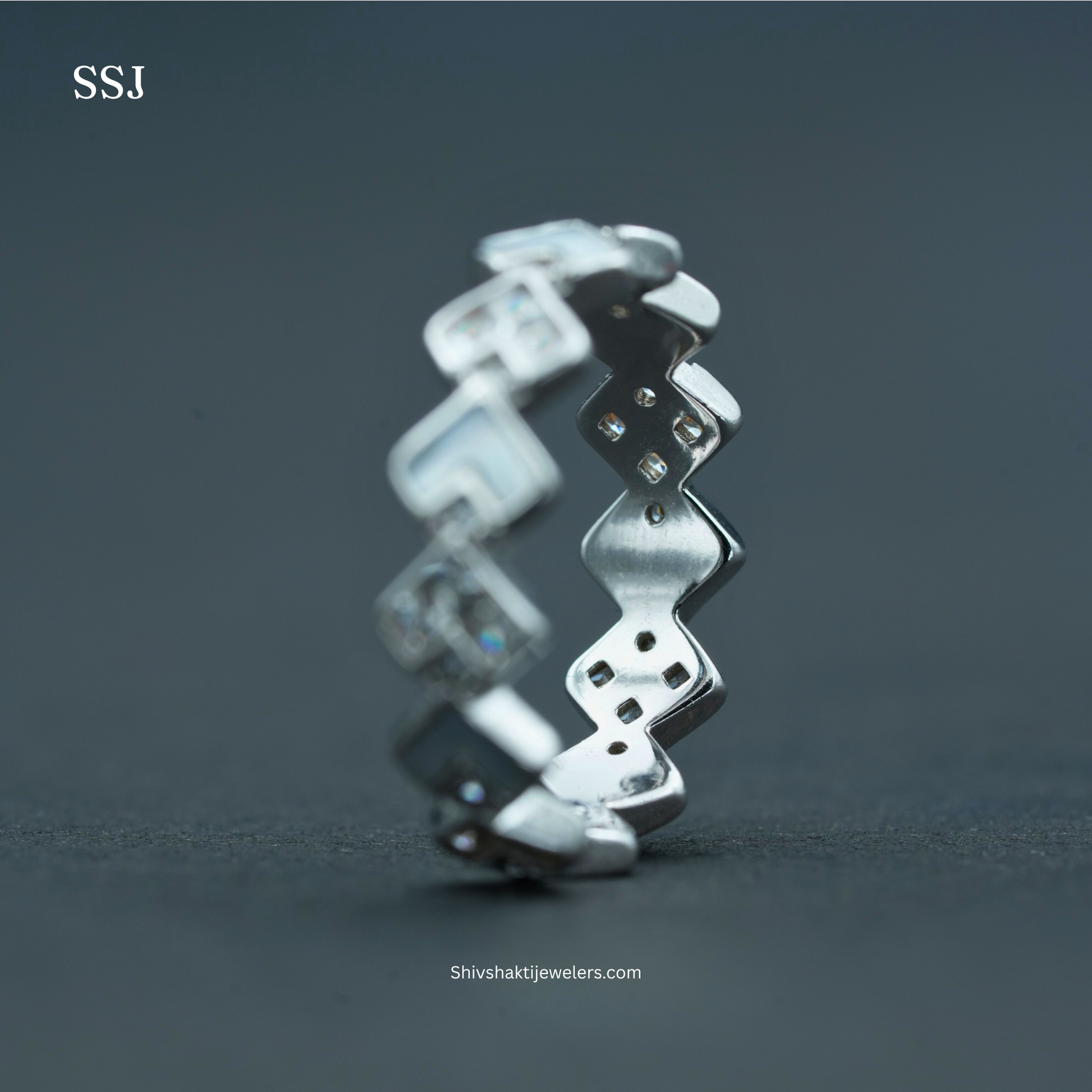 Silver ring with zigzag design on a dark gray background