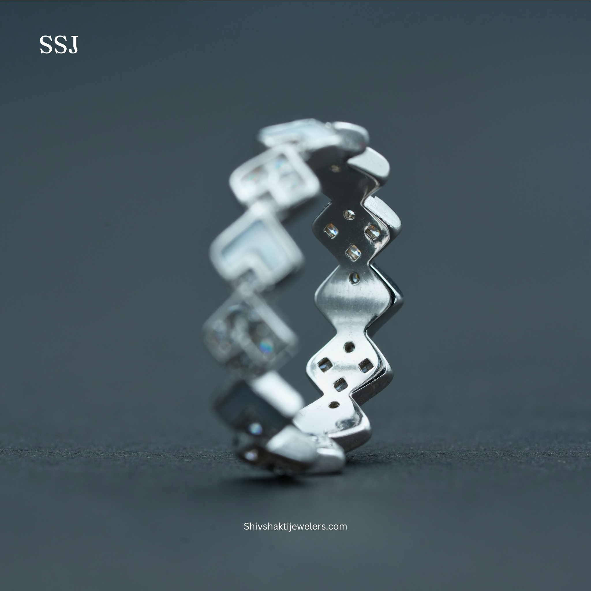 Silver ring with zigzag design on a dark gray background