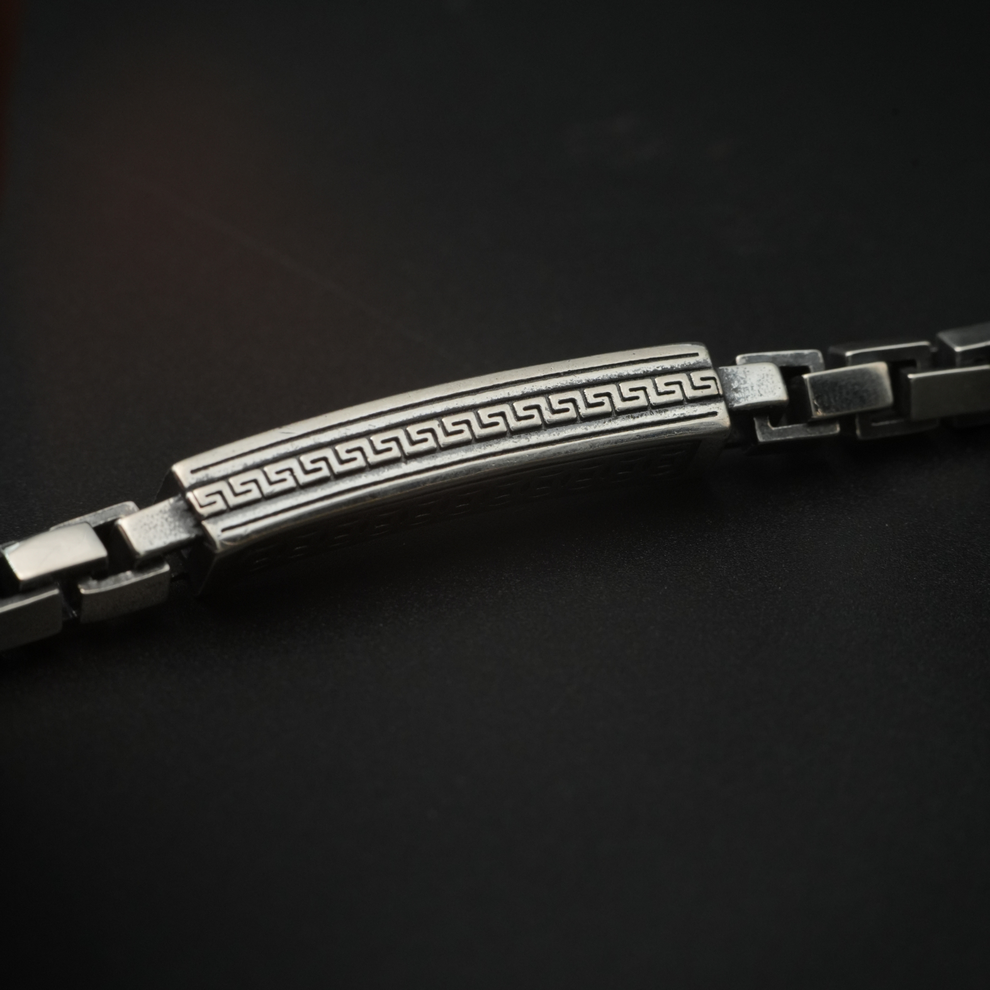 Close-up of engraved Greek key silver bar bracelet with square links