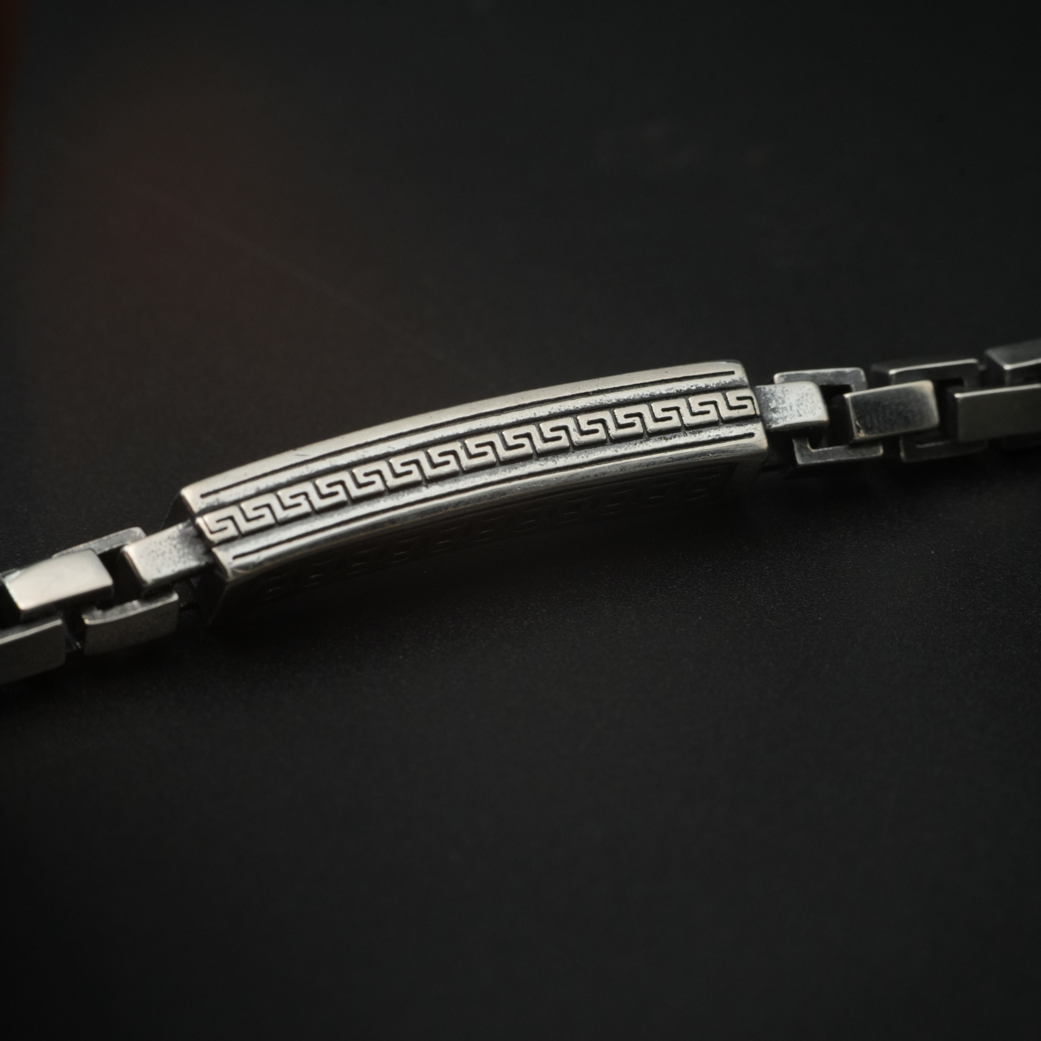 Close-up of engraved Greek key silver bar bracelet with square links